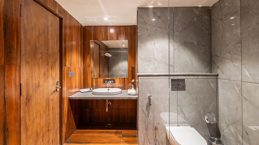 Deluxe King Room bathroom with sleek wooden paneling and marble counters at Clarks Inn Suites Jaipur, Ajmer Road